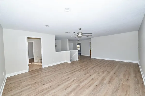 an empty room with wooden floor fan and windows
