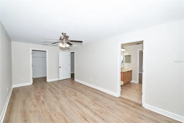an empty room with wooden floor fan and windows