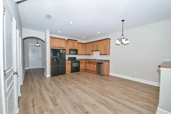 a kitchen with granite countertop wooden floors stainless steel appliances and a counter space
