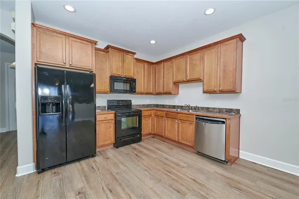 a kitchen with stainless steel appliances granite countertop a refrigerator a sink a stove and a wooden floors