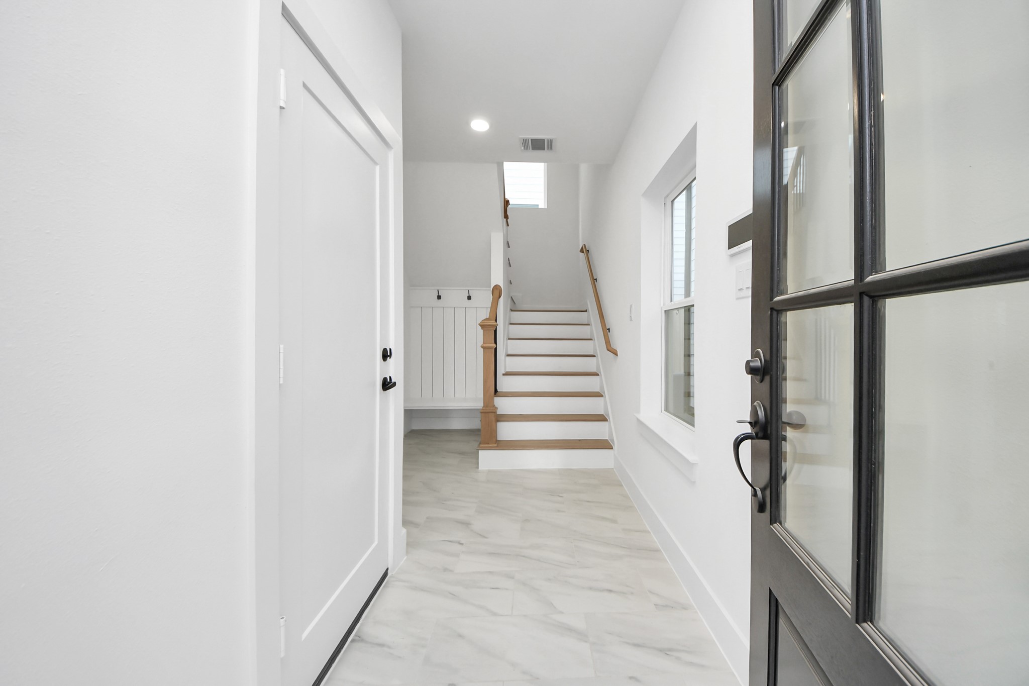 723 Marcella Street, Unit D Houston, TX 77091 - Photo 4 of 22 Enter thru the front door to begreeted by bright, clean entry way with a staircase leading up. The space features modern finishes with a tiled floor, natural light from a window, and a welcoming, neutral color palette.
