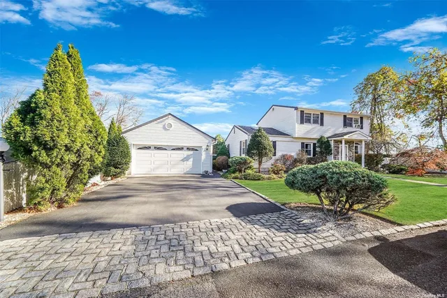 a view of a brick house with a yard plants and large tree