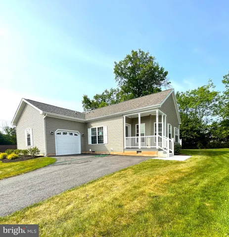 a front view of house with yard and trees in the background