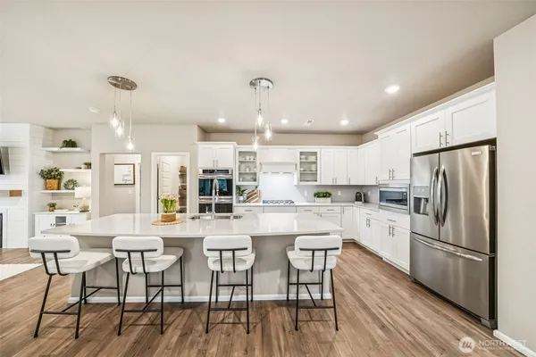 a kitchen with stainless steel appliances a dining table chairs stove refrigerator and cabinets