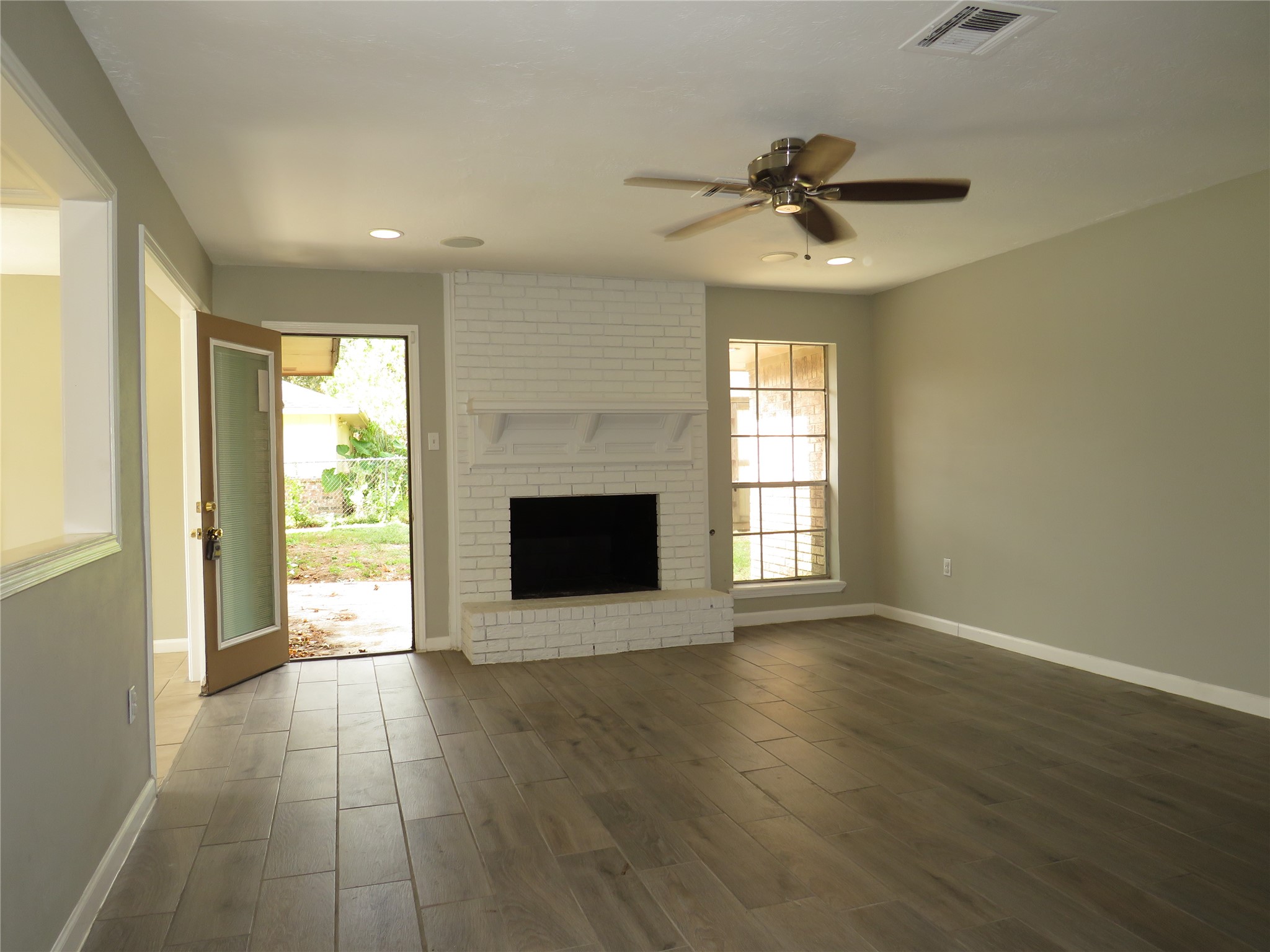 18703 Shay Lane Humble, TX 77346 - Photo 3 of 18 an empty room with wooden floor a fireplace and windows
