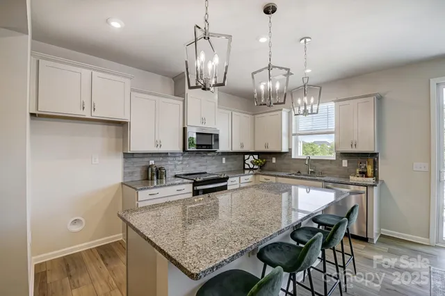 a kitchen with stainless steel appliances granite countertop a sink a stove and chairs