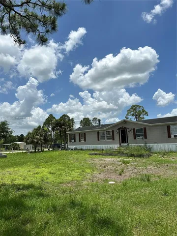 a view of a house with a big yard and a large tree