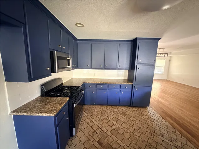 a kitchen with stainless steel appliances granite countertop a stove a refrigerator and a wooden cabinets