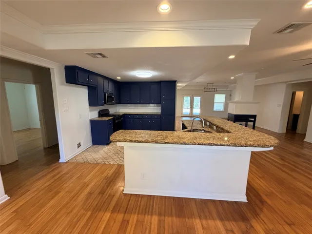 a large kitchen with stainless steel appliances wooden floors and wooden cabinets