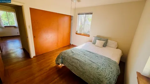 an empty room with wooden floor closet and windows