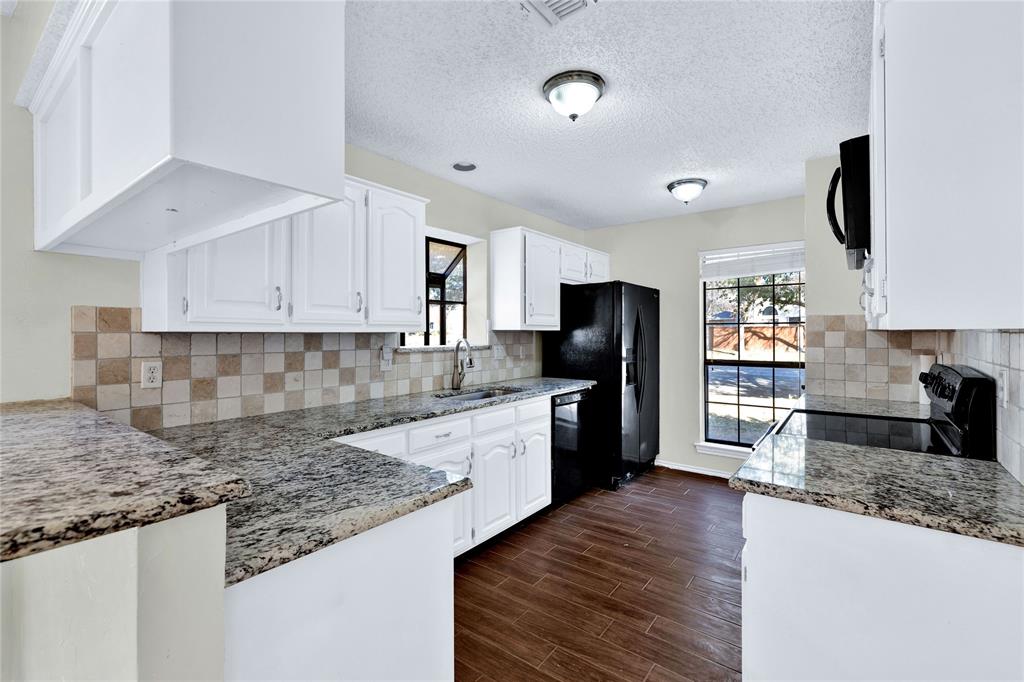 710 Cimarron Trail Irving, TX 75063 - Photo 17 of 39 a kitchen with granite countertop a refrigerator stove top oven and sink
