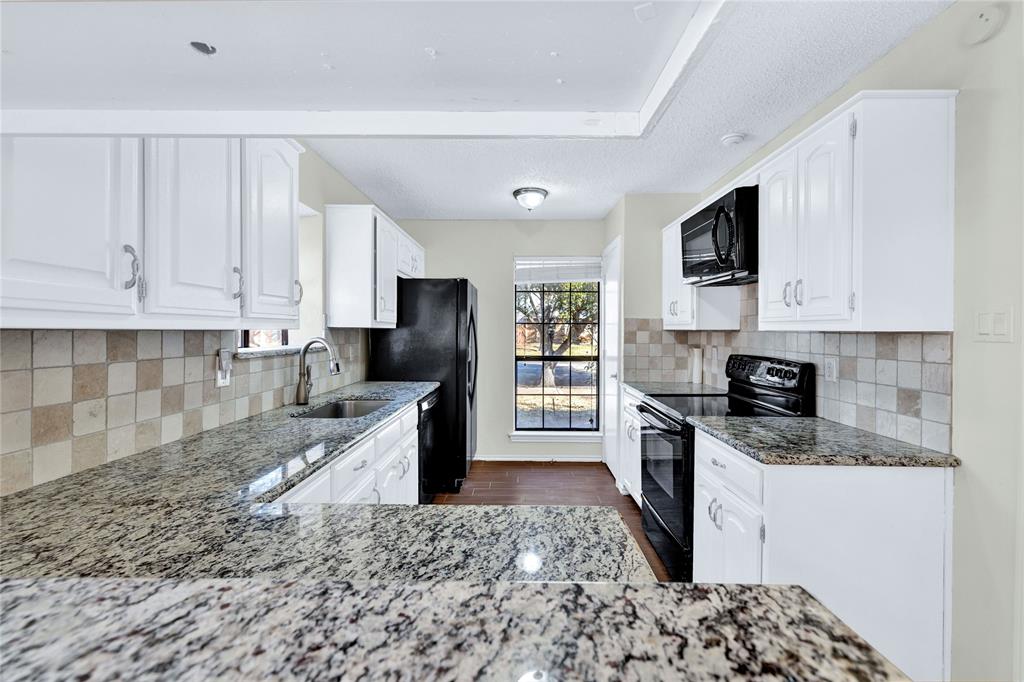 710 Cimarron Trail Irving, TX 75063 - Photo 18 of 39 a kitchen with granite countertop a sink a stove top oven and cabinetry