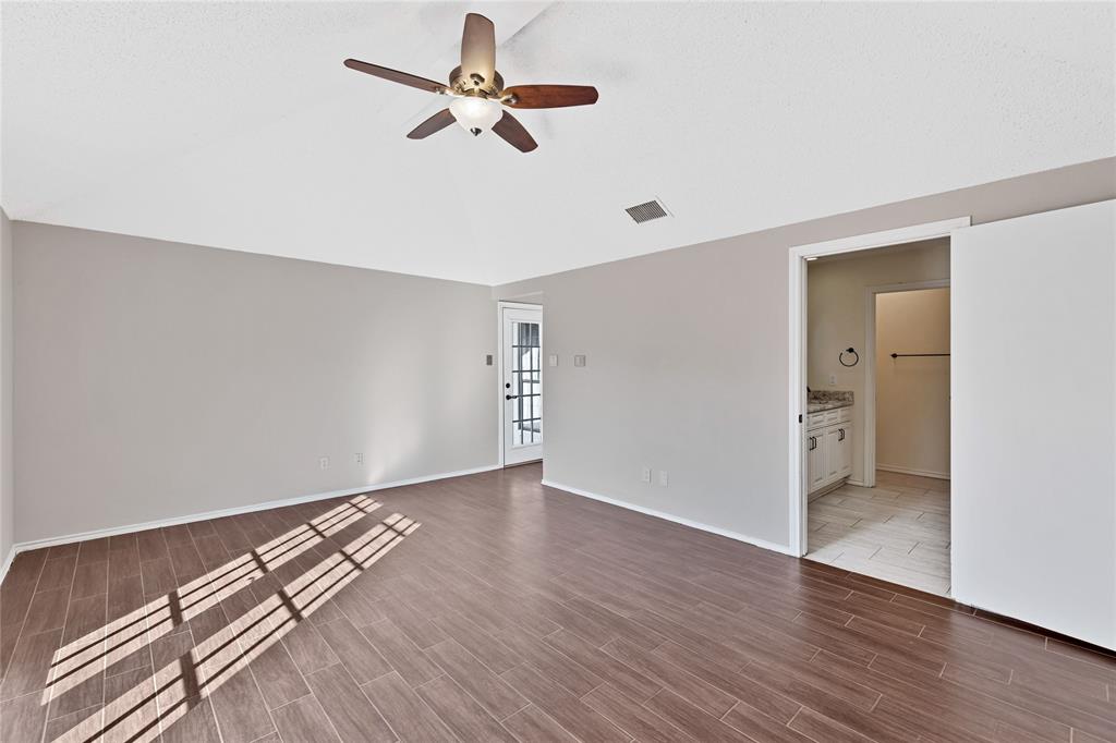 710 Cimarron Trail Irving, TX 75063 - Photo 10 of 39 an empty room with wooden floor chandelier fan and windows