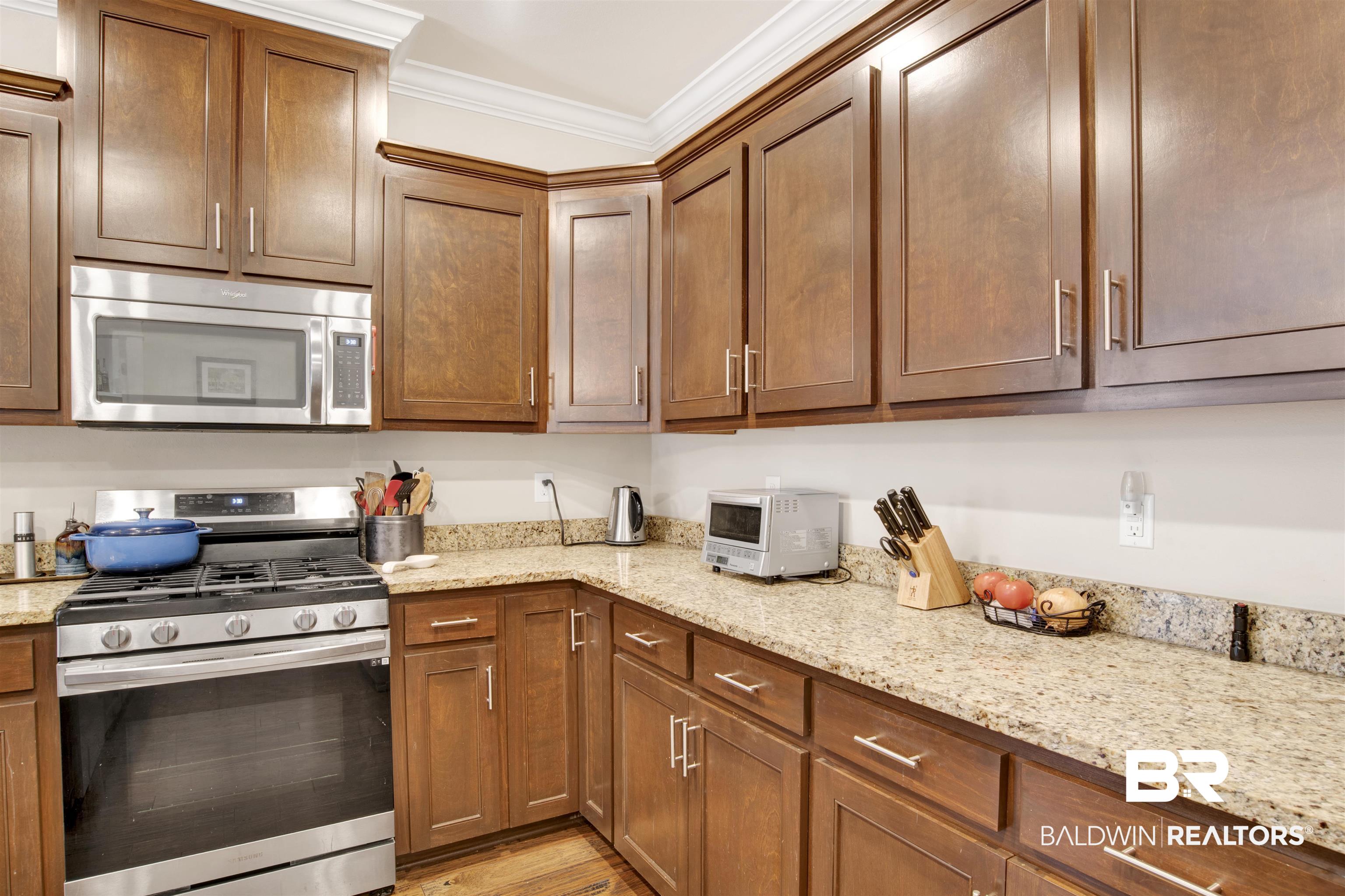 360 Scarlett Avenue Fairhope, AL 36532 - Photo 13 of 34 Kitchen featuring light wood-type flooring, light stone counters, appliances with stainless steel finishes, and crown molding