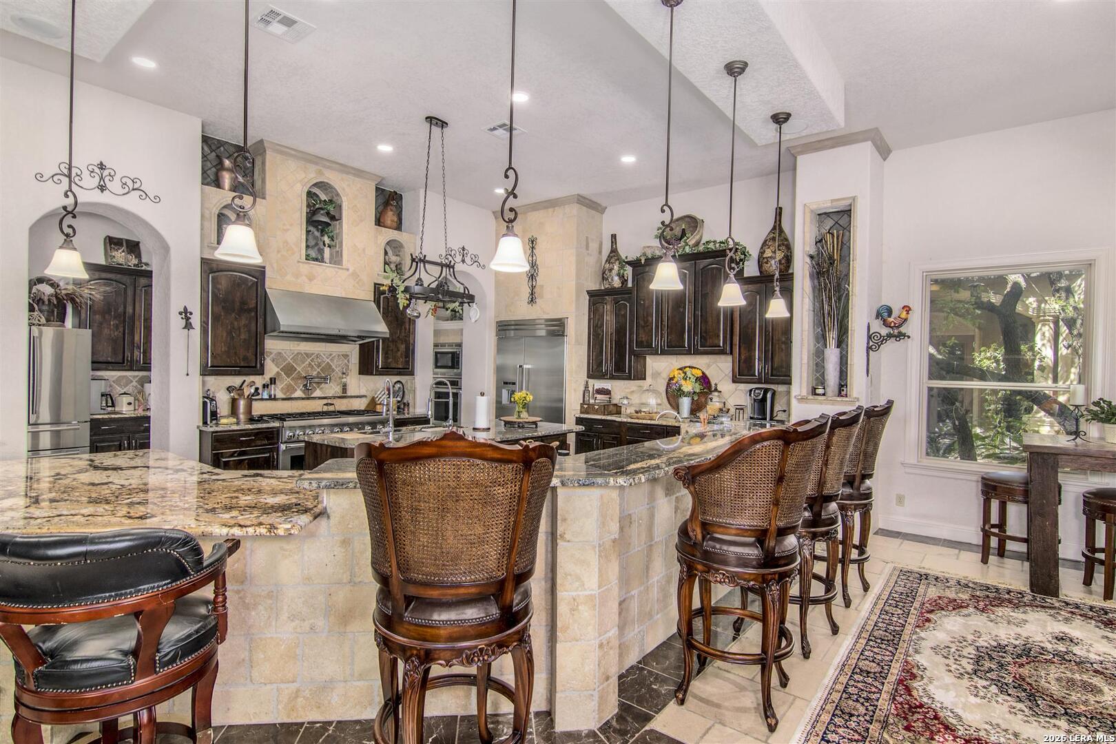9469 Canyon Mist Helotes, TX 78023 - Photo 15 of 50 a kitchen with stainless steel appliances kitchen island granite countertop a table chairs and a refrigerator