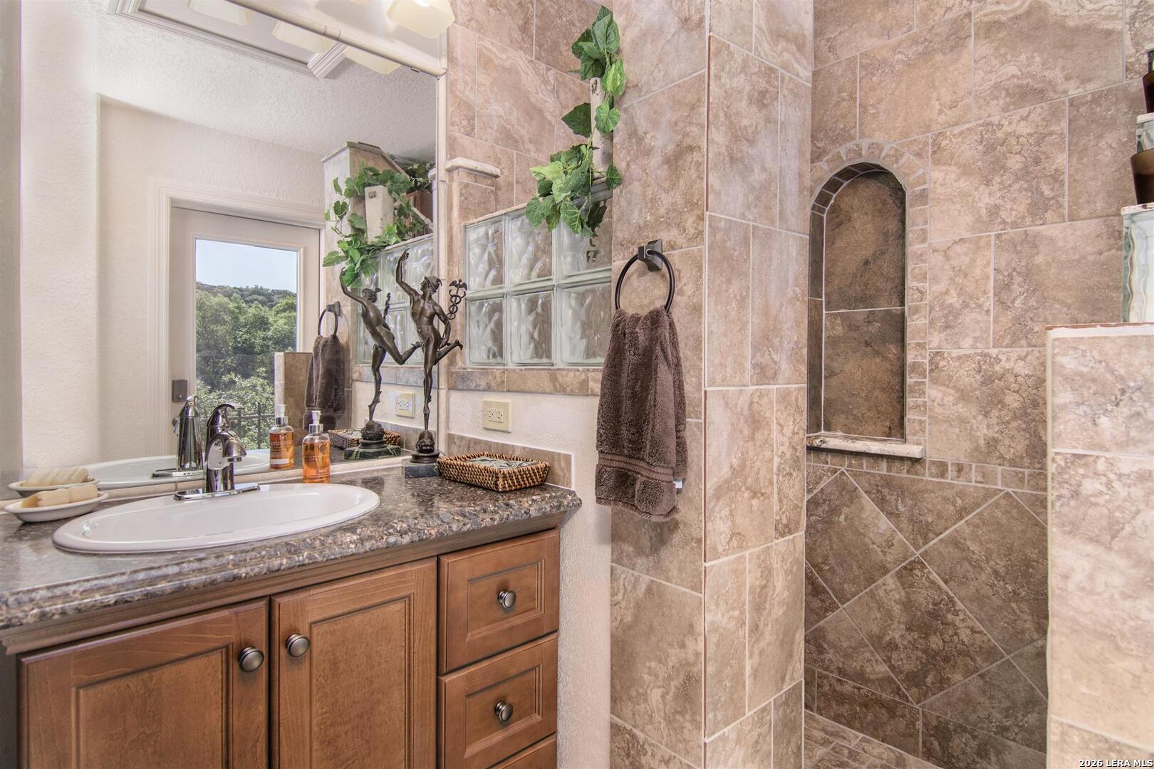 9469 Canyon Mist Helotes, TX 78023 - Photo 34 of 50 a bathroom with a granite countertop sink and a mirror