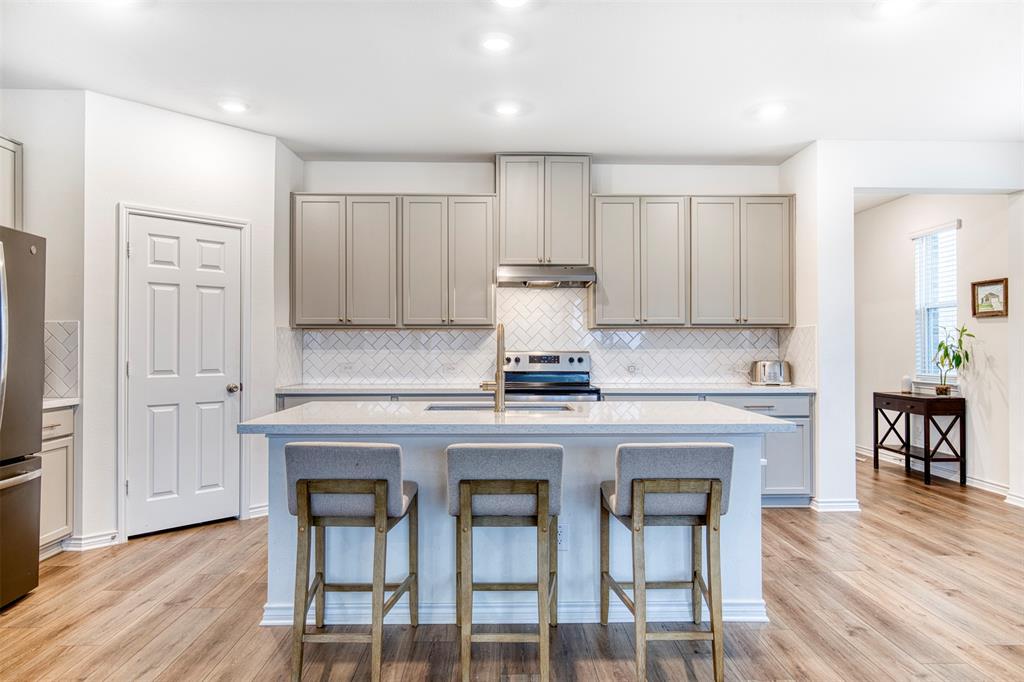 2513 Wayne Avenue Aubrey, TX 76227 - Photo 13 of 27 a kitchen with a stove a sink cabinets and wooden floor