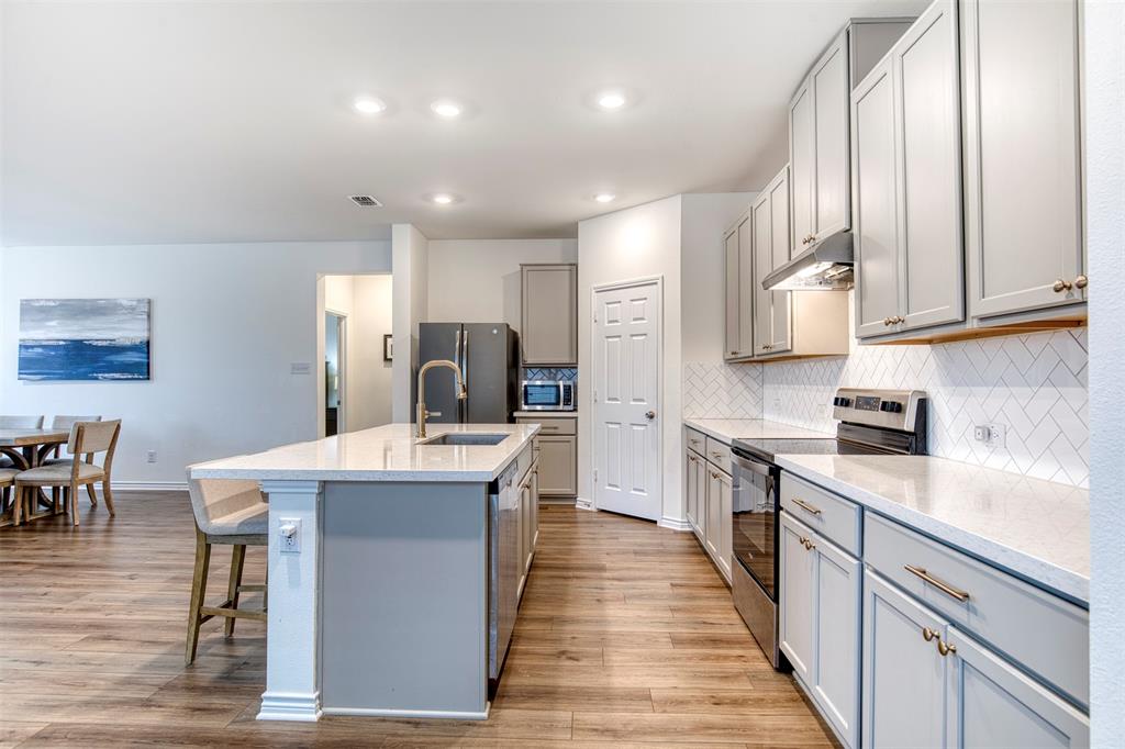 2513 Wayne Avenue Aubrey, TX 76227 - Photo 10 of 27 a kitchen with stainless steel appliances kitchen island granite countertop a sink counter space and cabinets