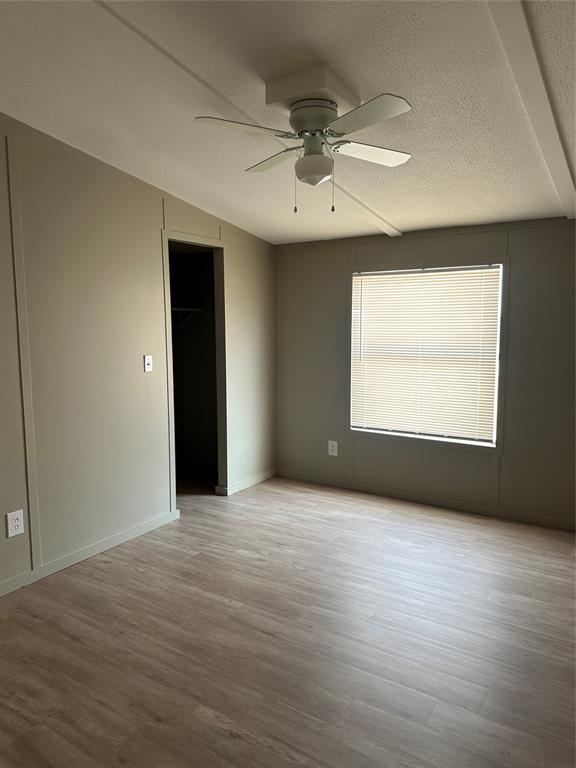 1109 Market Street Tye, TX 79563 - Photo 17 of 20 an empty room with wooden floor chandelier fan and windows