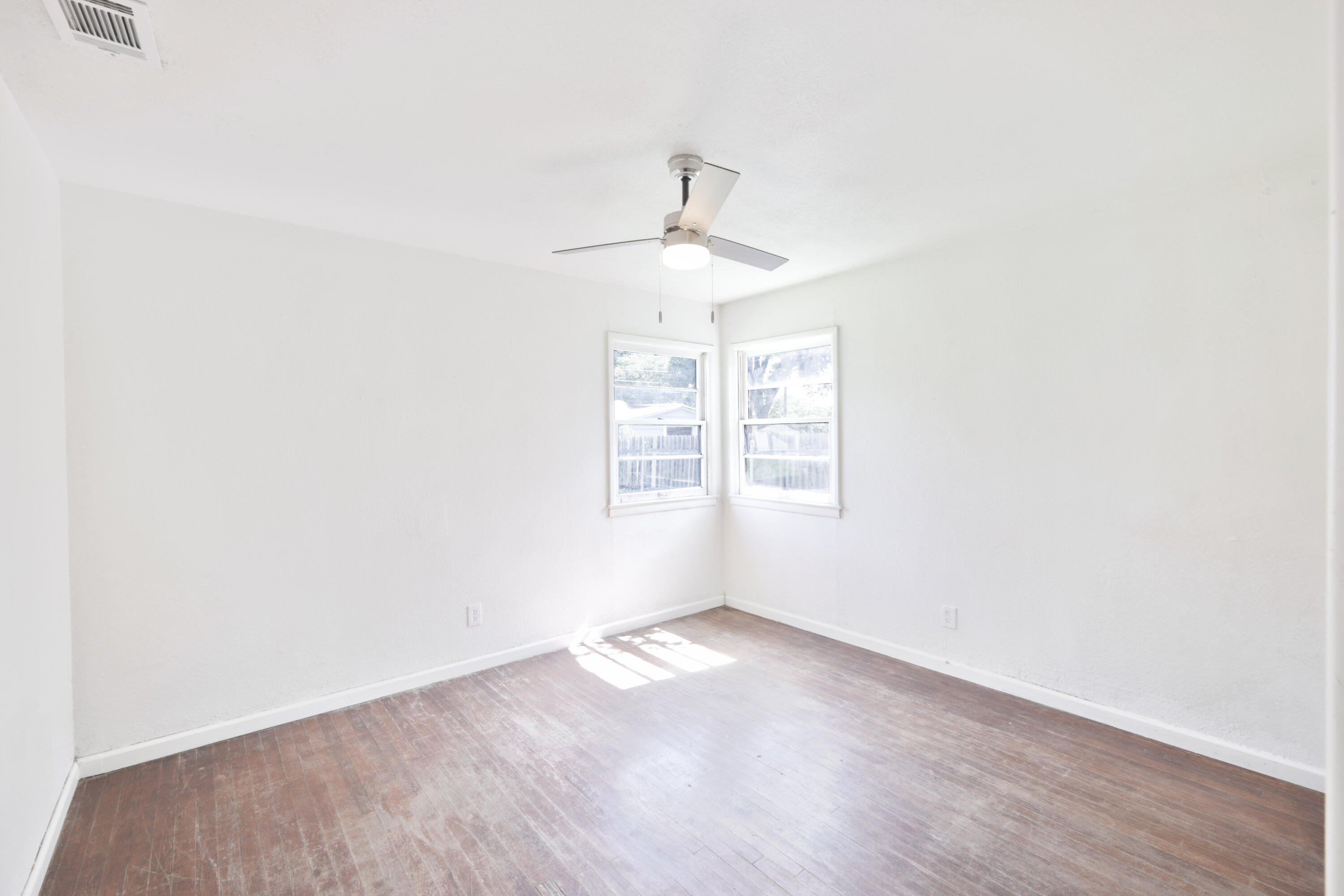 3812 31st Street Lubbock, TX 79410 - Photo 11 of 16 an empty room with wooden floor chandelier fan and windows