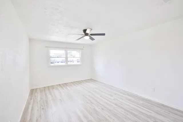 an empty room with wooden floor and ceiling fan