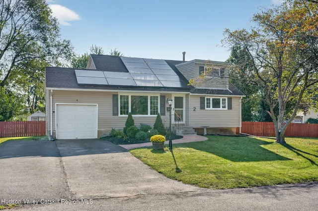 a front view of a house with garden and trees
