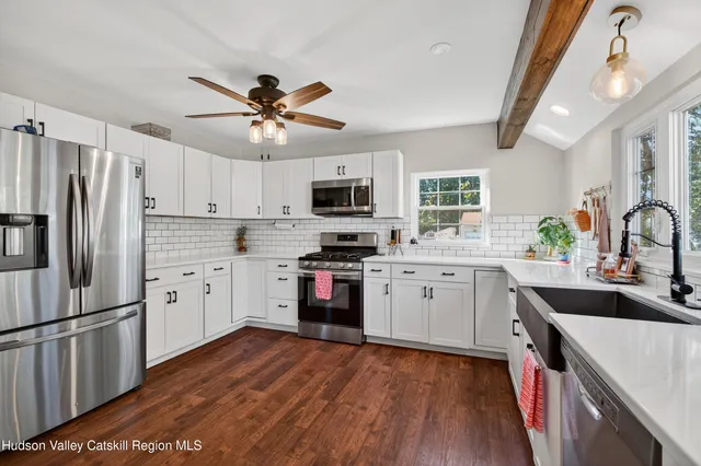 a kitchen with white cabinets stainless steel appliances a sink and a refrigerator