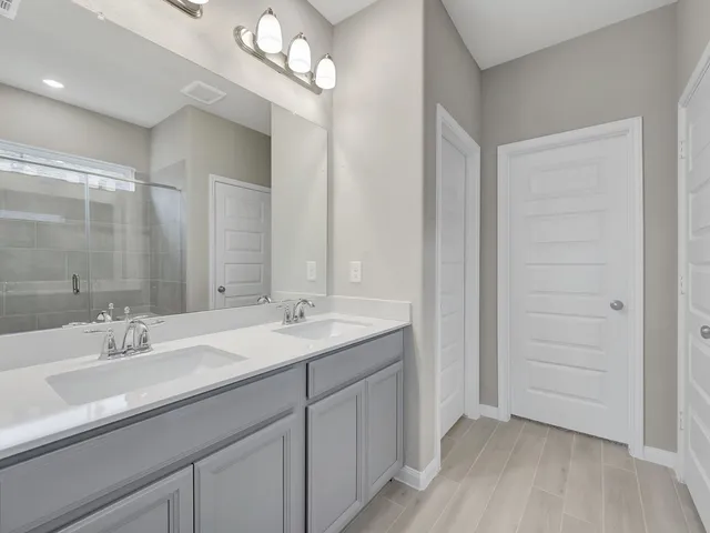 a bathroom with a double vanity sink a mirror and a shower