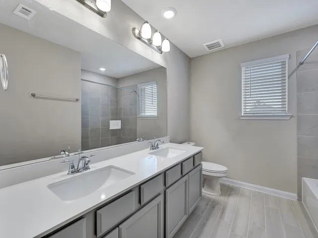 a bathroom with a double vanity sink a mirror and a toilet