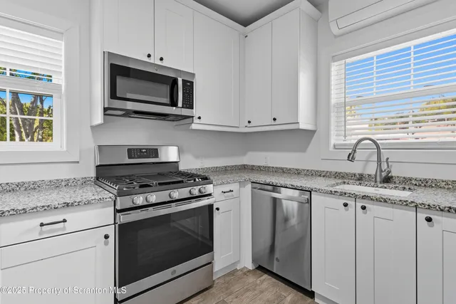 a kitchen with granite countertop a stove top oven microwave and cabinets