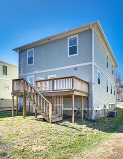 a view of a house with wooden deck and a yard