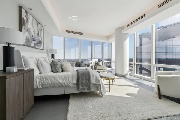 a spacious bedroom with a bed a couch and large window