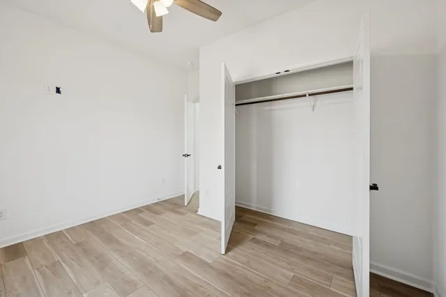 an empty room with a ceiling fan and window