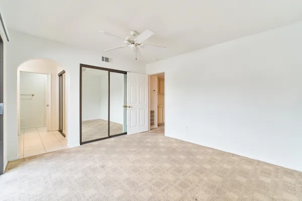 an empty room with a ceiling fan and windows