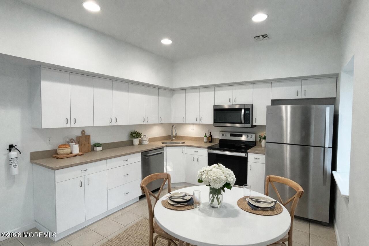 101 Main Street Farmingdale, NJ 07727 - Photo 4 of 12 a kitchen with stainless steel appliances granite countertop a sink a stove a refrigerator and white cabinets with wooden floor