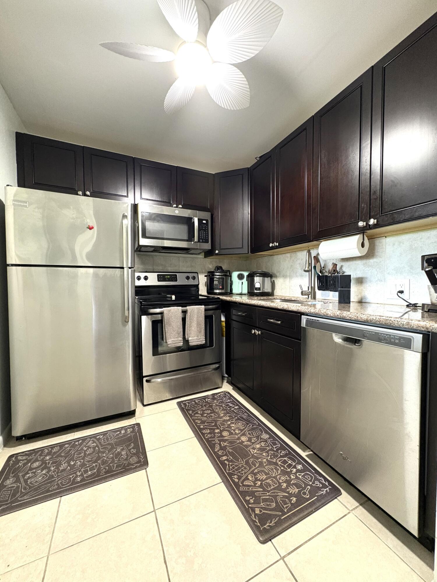 a kitchen with stainless steel appliances granite countertop a refrigerator a sink a stove and oven