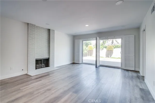 an empty room with wooden floor and a fireplace