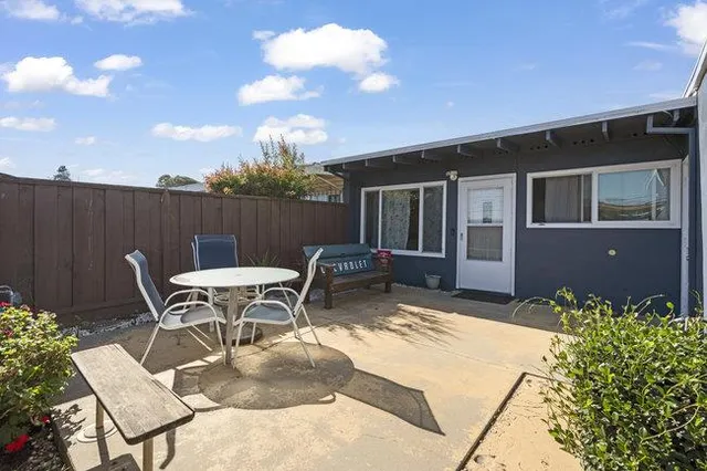 a view of a patio with table and chairs and potted plants with wooden fence