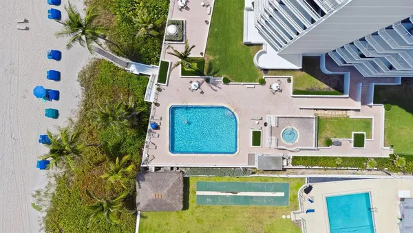 a view of a swimming pool with a yard and palm trees