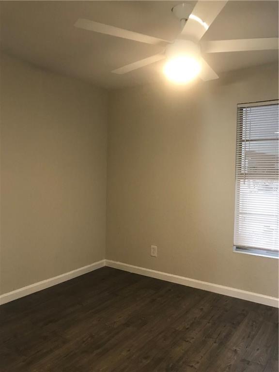 1119 Spur Street, Unit A Austin, TX 78721 - Photo 8 of 10 Rich wood-look flooring grounds this sun-filled bedroom featuring a modern ceiling fan.