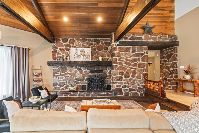 460 Omni Point Road Central Valley, UT 84754 - Photo 9 of 101 Spacious living area featuring a prominent stone fireplace, 3/4 inch harwoood oak cloors vaulted ceiling with exposed beams, wood-finish flooring, and a stone accent wall