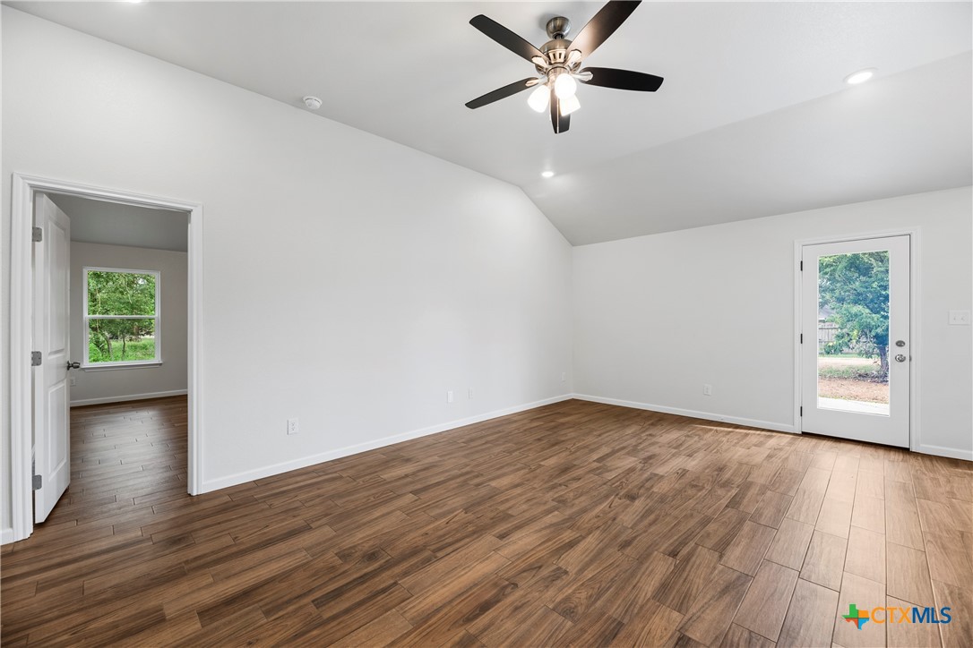 230 Plum Street Luling, TX 78648 - Photo 14 of 33 an empty room with wooden floor chandelier fan and windows