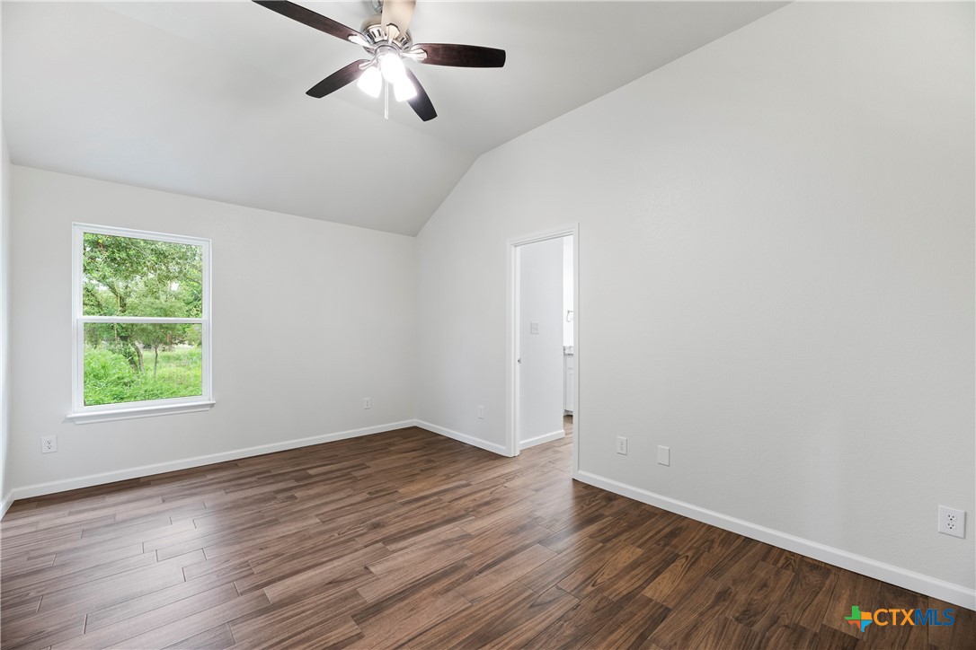 230 Plum Street Luling, TX 78648 - Photo 23 of 33 an empty room with wooden floor ceiling fan and windows