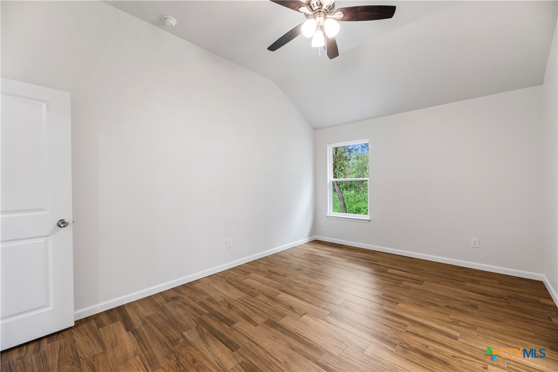 230 Plum Street Luling, TX 78648 - Photo 27 of 33 an empty room with wooden floor chandelier fan and windows