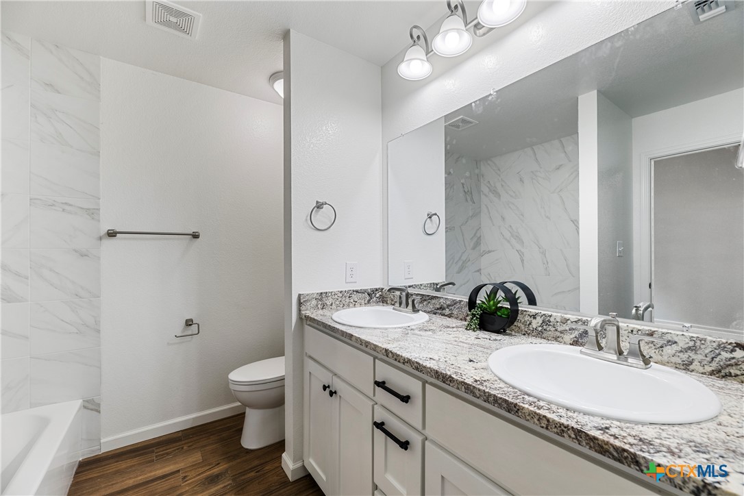 230 Plum Street Luling, TX 78648 - Photo 28 of 33 a bathroom with a granite countertop double vanity sink a mirror and a toilet