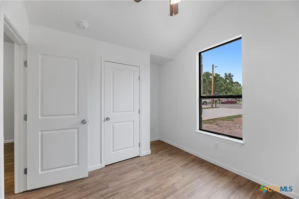 an empty room with wooden floor closet and windows