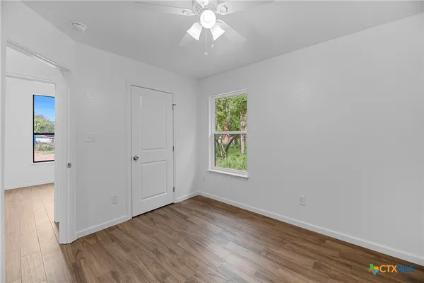 an empty room with wooden floor closet and windows