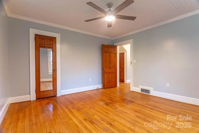 a view of an empty room and chandelier fan