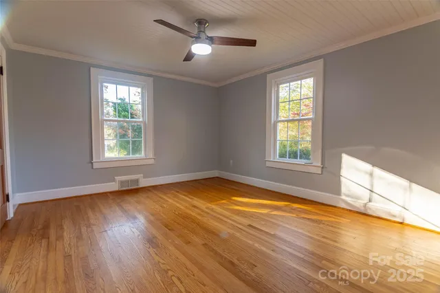 a view of empty room with wooden floor and fan