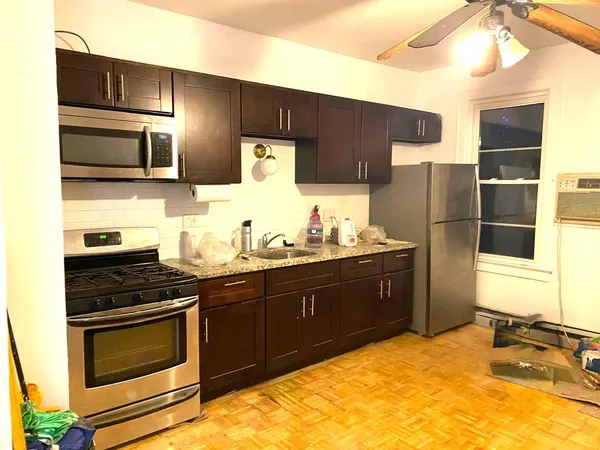a kitchen with stainless steel appliances kitchen island granite countertop a stove refrigerator and microwave